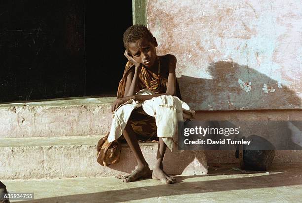 Starving young boy rests on a door stoop in Mogadishu.