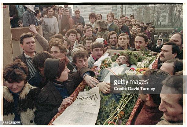 Man killed during the 1989 Romanian Revolution lies in a flower-filled coffin before his burial at the Belu cemetery. The newspaper lying on top of...
