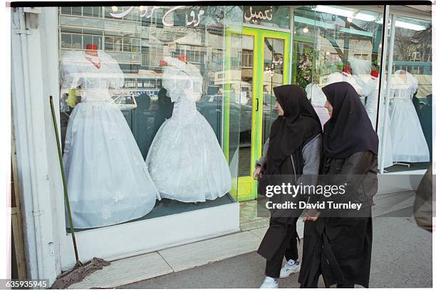 Two Iranian women walk past a bridal shop in an affluent shopping area of Tehran.