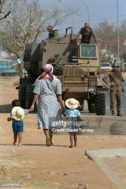 Mother walks with her young son and daughter through the streets of Soweto, during a state of emergency in which the South African military occupies...