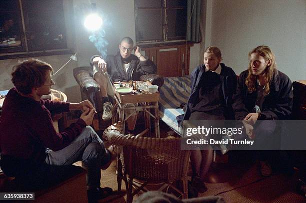 Group of friends talk and smoke cigarettes in a run-down room in Prenzlauer Berg, East Berlin. The derelict Prenzlauer Berg district became populated...