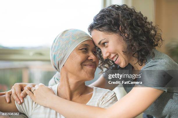 ethnische erwachsene krebspatientin umarmt ihre tochter - cancer cell stock-fotos und bilder