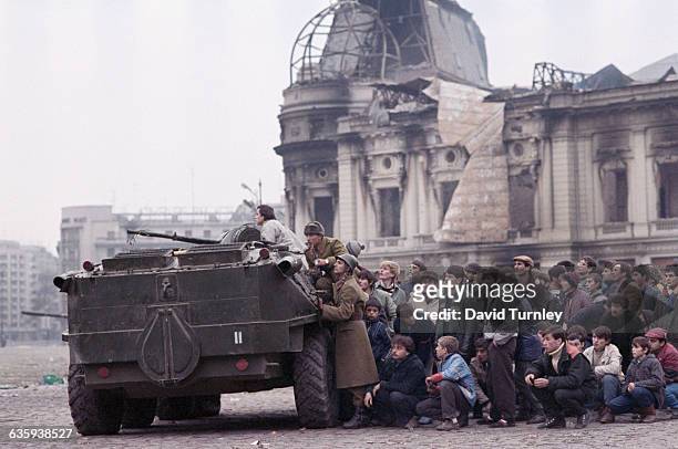 Crowd of civilians hide behind a People's Army tank in Republic Square after the overthrow of Romanian dictator Nicolae Ceausescu.