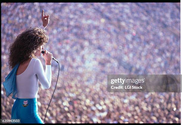 Kevin Cronin of REO Speedwagon sings to a crowded arena.