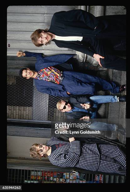 The pop/rock group Level 42 is shown seated and standing around a doorway outdoors.
