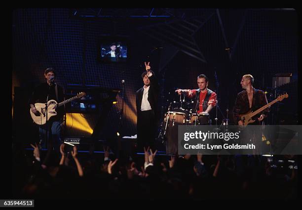 From left, Mike Mills and Michael Stipe of R.E.M., performing on stage with Larry Mullen, Jr. And Adam Clayton of U2. They are playing a concert at...