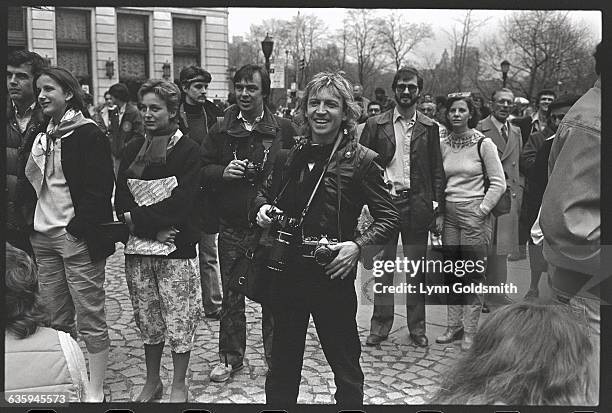 Surrounded by fans, guitarist Andy Summers of rock band The Police holds a camera and smiles.