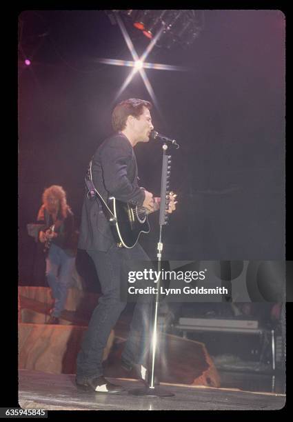 Country music star Clint Black plays the guitar and sings during a concert performance.