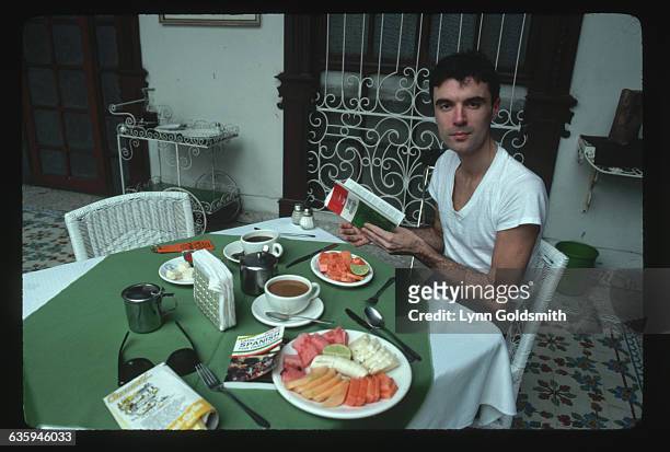 David Byrne, lead vocalist for the "Talking Heads", reads a Mexico guidebook over a cup of coffee.