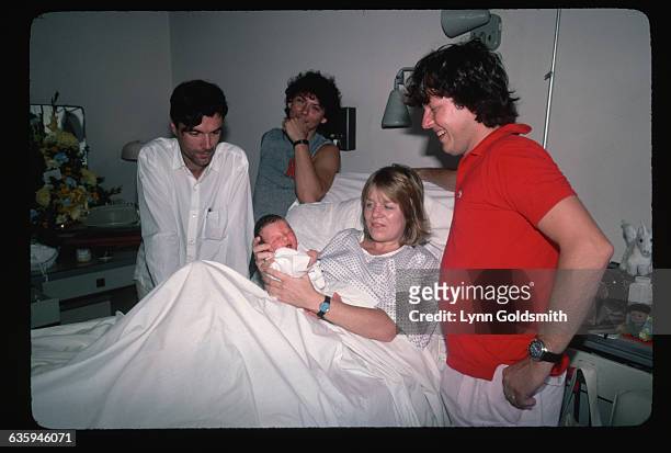 David Byrne and Jerry Harrison visit Tina Weymouth and Chris Frantz in the hospital after the birth of their baby.