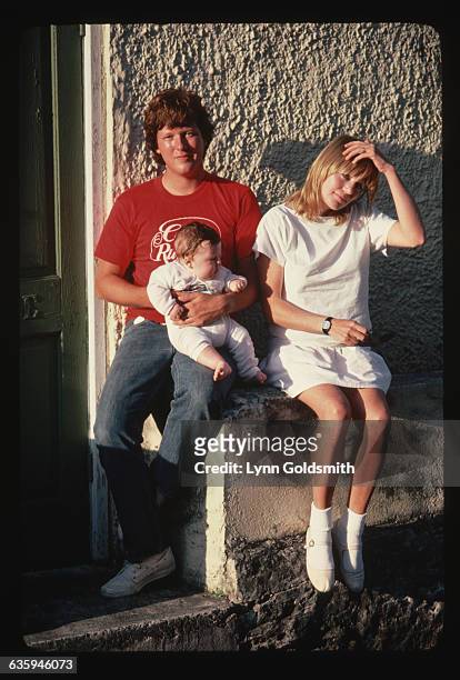 Tina Weymouth runs her fingers through her hair as she sits beside her husband Chris Frantz, and their new baby.