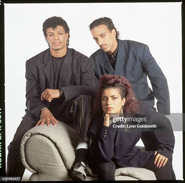 Picture shows a picture of the pop group, Lisa Lisa & Cult Jam, posing in a studio on a chair together.