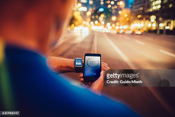 man synchronising smartwatch and mobile phone. - ウェアラブルコンピュータ ストックフォトと画像