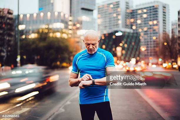man checking smartwatch in city. - active senior man stock-fotos und bilder
