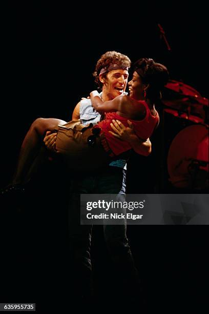 Bruce Springsteen lifts a female fan off her feet at his concert.