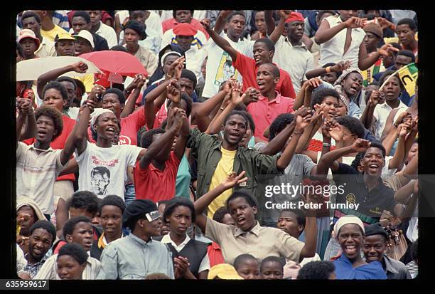 Young black South Africans cheer and raise their fists for Nelson Mandela at a rally celebrating his release from prison at a Soweto stadium.