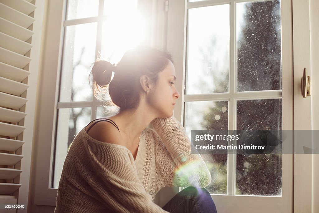 Unhappy housewife sitting near the window