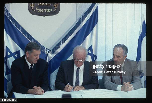 Norwegian Foreign Minister Johan Jorgen Holst, left, facilitates the signing of the peace agreement between Israel and the Palestine Liberation...