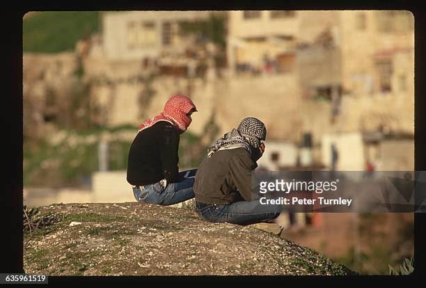 Two young Palestinians look out over East Jerusalem, wearing kaffiyehs to mask their faces, like many stone throwers during the Intifada.