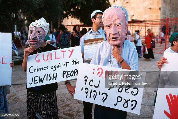 Israeli settlers in the West Bank town of Hebron wear masks depicting Palestinian leader Yasser Arafat and Israeli Prime Minister Yitzhak Rabin...
