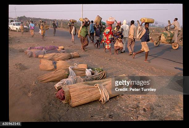 Rwandans walk past the dead bodies of some of the thousands of refugees who fled the war in Rwanda and then fell victim to a cholera epidemic in a...