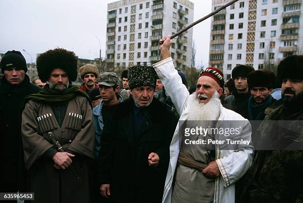 Group of Muslim men listen to an elderly Muslim man shout.
