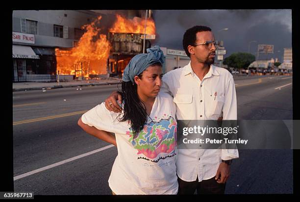 Onlookers watch buildings burn and smoke clouds fill the LA skies as a result of the 1992 riots.