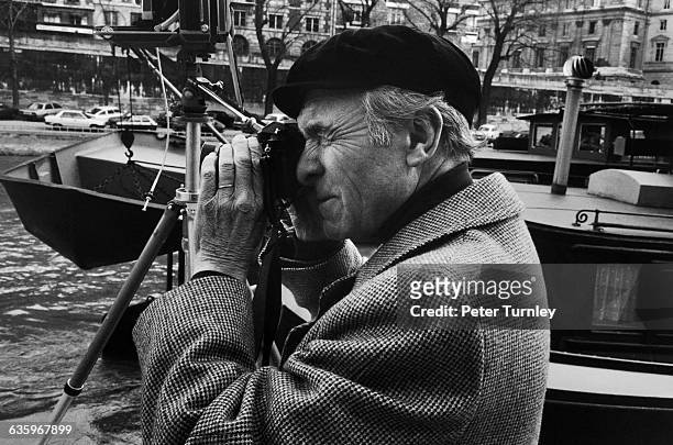 Photographer Robert Doisneau shoots photos along the Seine next to barges and boats.