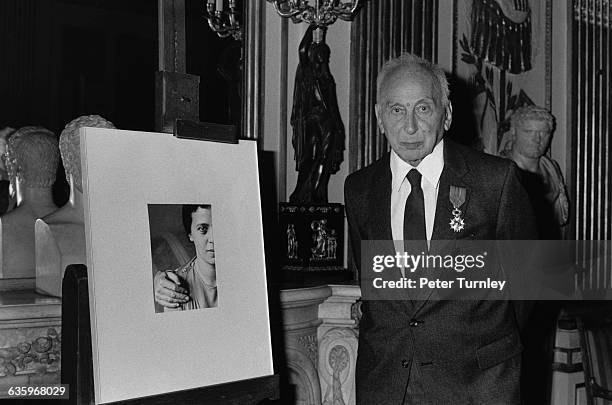 Hungarian born photographer Andre Kertesz stands beside a portrait of his wife which he photographed. Kertesz wears the medal he was awarded by the...