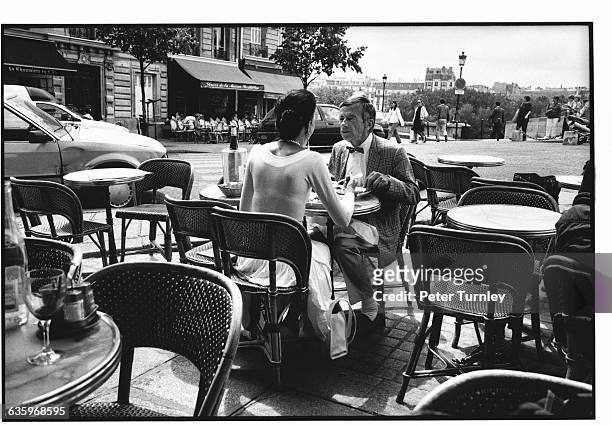 An elegant Parisian couple share intimate conversation while dining al fresco at the Brasserie de l'Ile Saint Louis.