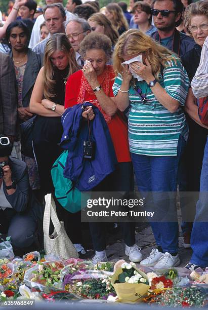 Weeping mourners look at flower bouquets placed outside Kensington Palace, which was the official residence of Princess Diana. In an overwhelming...