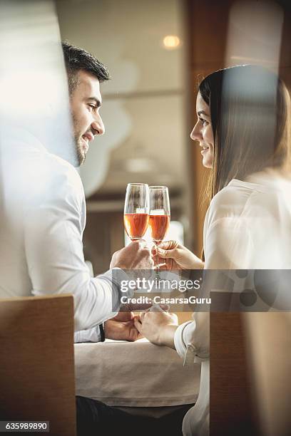 young couple on a romantic date in a restaurant - tafel voor twee stockfoto's en -beelden