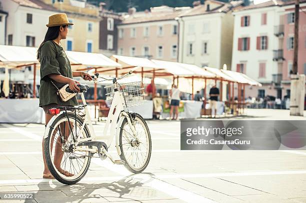 thai woman walking with bicycle on the square of piran - piran slovenia stock pictures, royalty-free photos & images