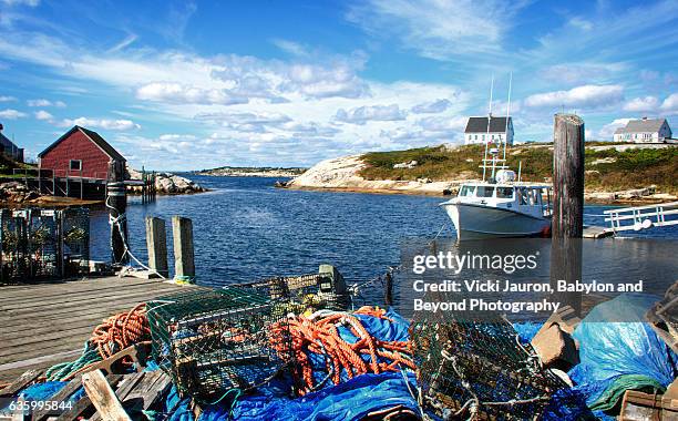 lobster trap in foreground against peggys cove, nova scotia, canada - peggys cove stock-fotos und bilder