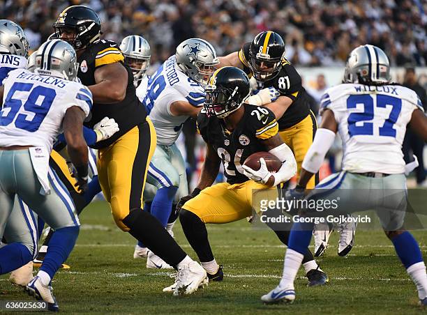 Running back Le'Veon Bell of the Pittsburgh Steelers runs with football as offensive lineman Ramon Foster and tight end Jesse James block during a...