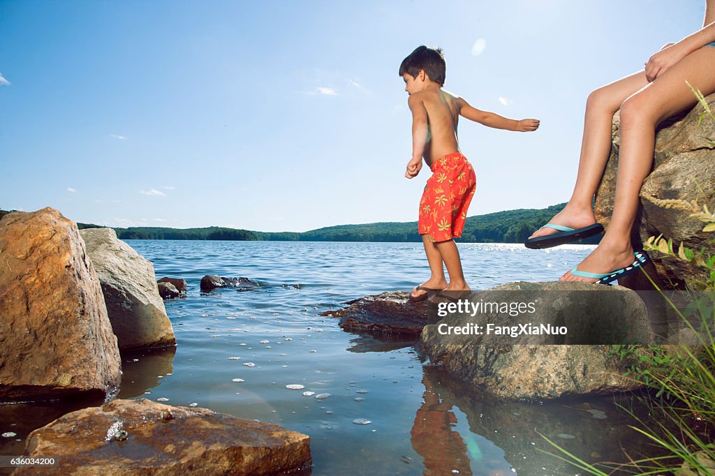 Junge werfen Felsen in See