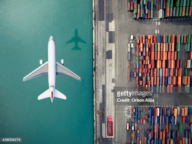 flugzeug fliegt über containerhafen - freight transportation stock-fotos und bilder