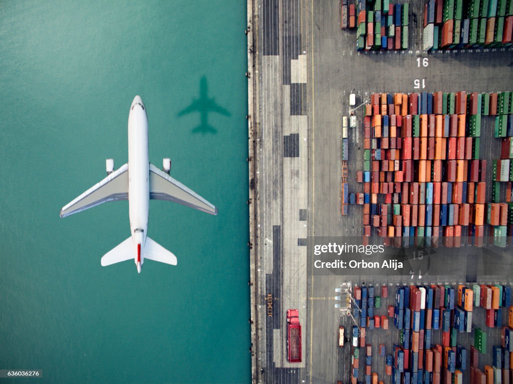 Airplane flying over container port