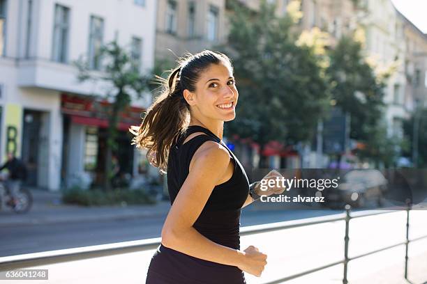 happy young woman jogging in city - happy people running stockfoto's en -beelden