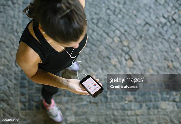frau überwacht ihren trainingsfortschritt auf fitness-app - smartphone musik stock-fotos und bilder