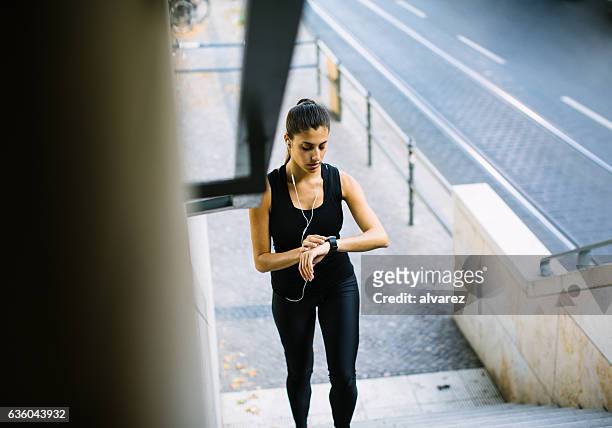 donna sana sui gradini che controllano l'orologio intelligente - marcare foto e immagini stock