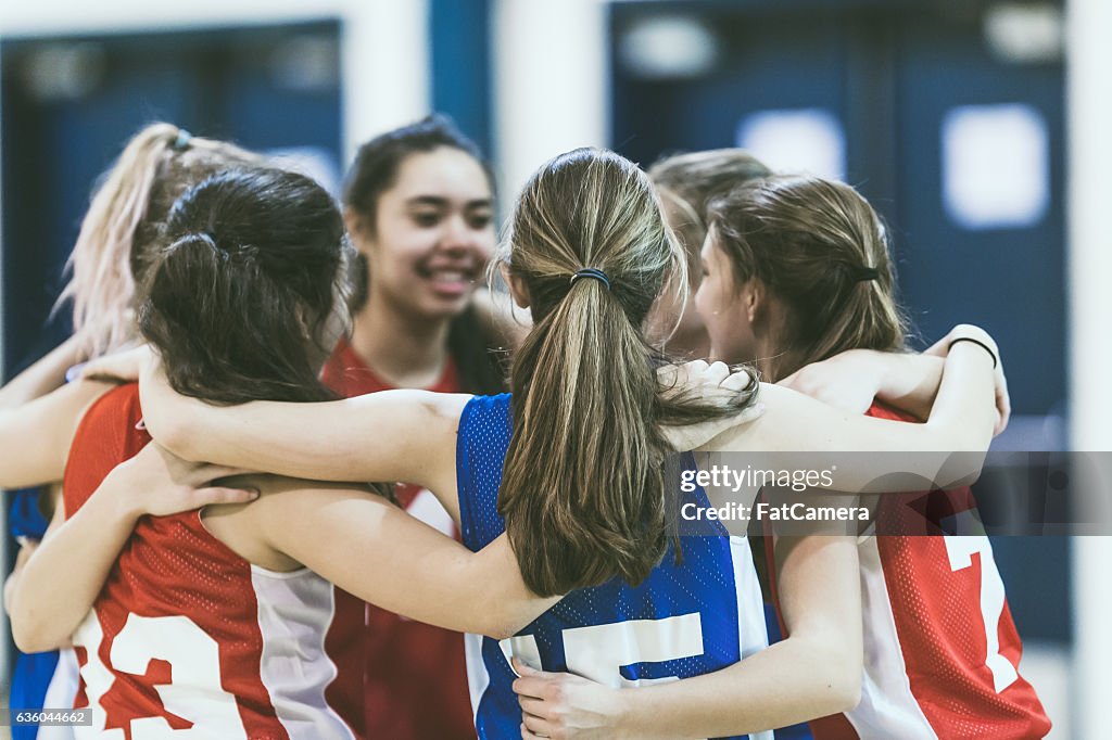 Group of female high school basketball players encouraging one another