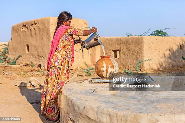 indian woman collecting water, rajasthan - putten stockfoto's en -beelden