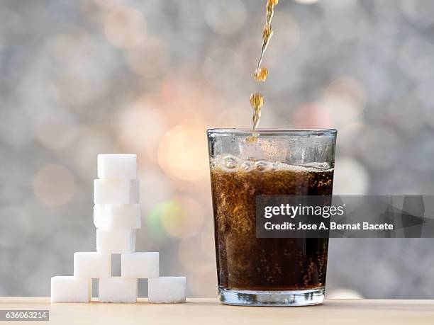 fill a glass of refreshment of tail sweetened, with his equivalent close to the glass in cubes of sugar - frothy drink stock-fotos und bilder