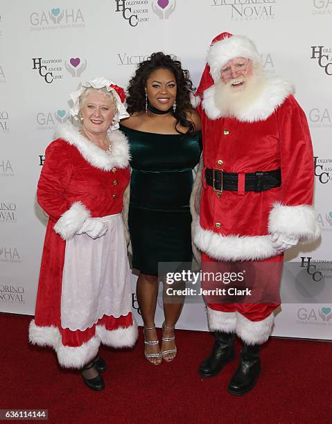 Dominique Simpson of CMR PR poses with Mrs. Claus and Santa Claus at the Victorino Noval Foundation Christmas Party on December 17, 2016 in Beverly...