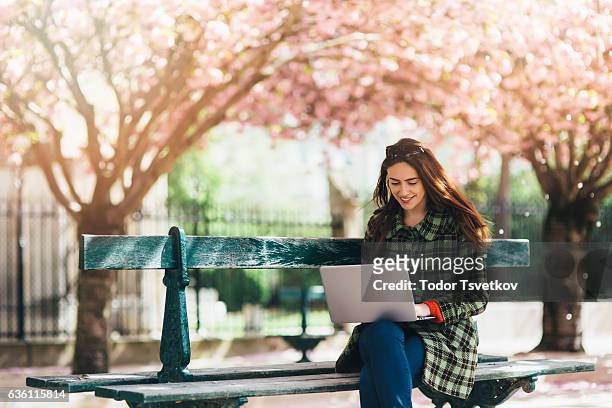 屋外で使っている女性はラップトップ - フランス　公園 ストックフォトと画像