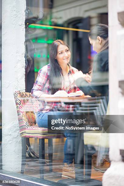 girl friends sitting together in cafe, chatting, drinking coffe - publik stockfoto's en -beelden