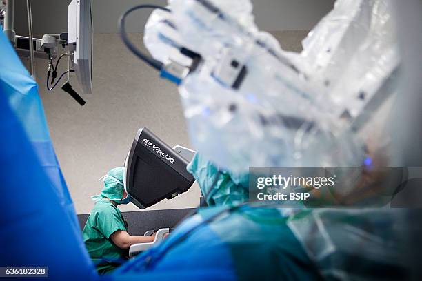 Reportage in an operating theatre during a hysterectomy using the da Vinci robot¬. The surgeon steers the robot from the console.