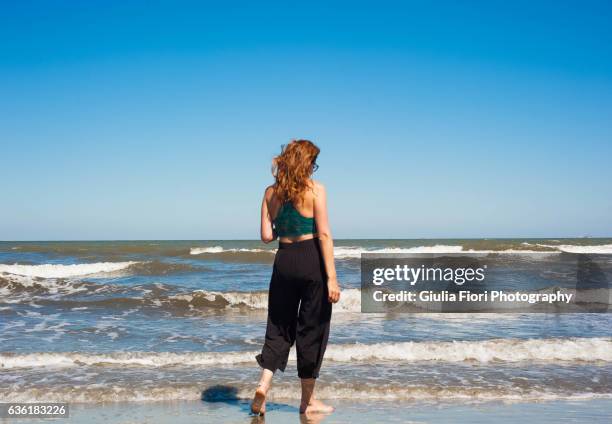young woman walking on the beach - pantalon mi mollet photos et images de collection