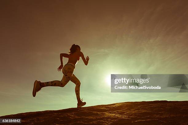 hispanic women running up a granite boulder - uphill stockfoto's en -beelden